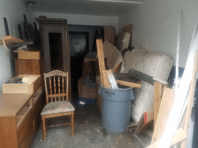 Interior of a cluttered storage unit filled with furniture and other household items.